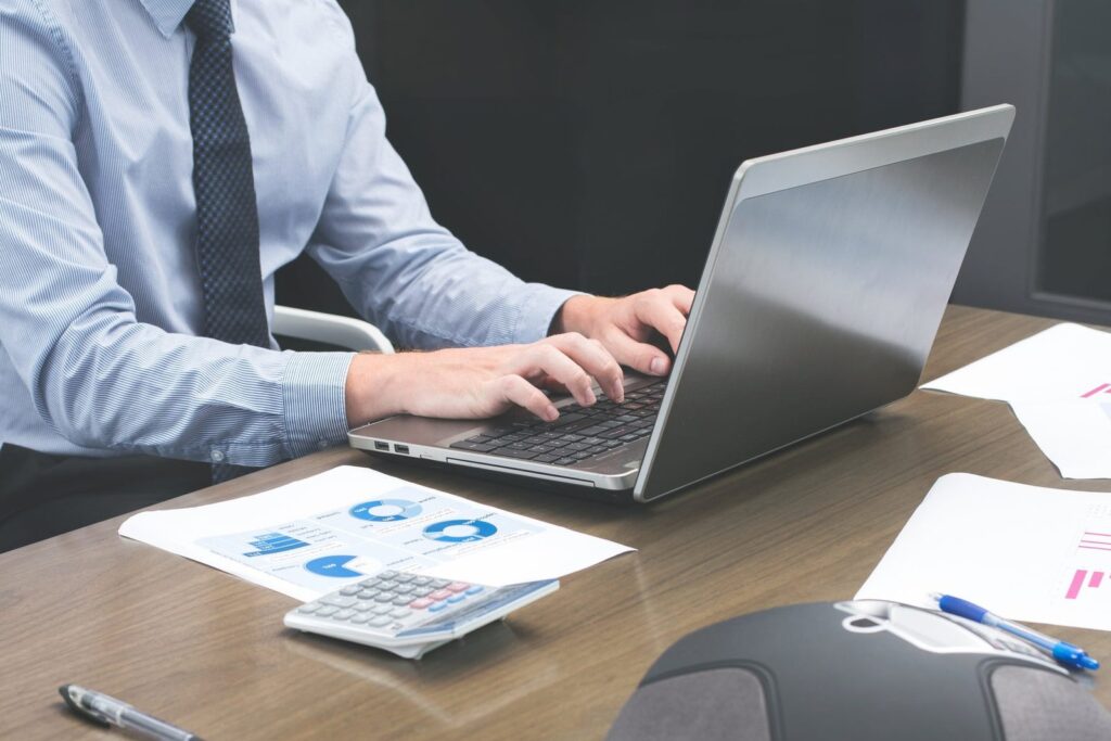 Medical billing and coding on a laptop beside printed reports